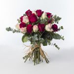 Flower bouquet that contains pink and red roses surrounded with eucalyptus.